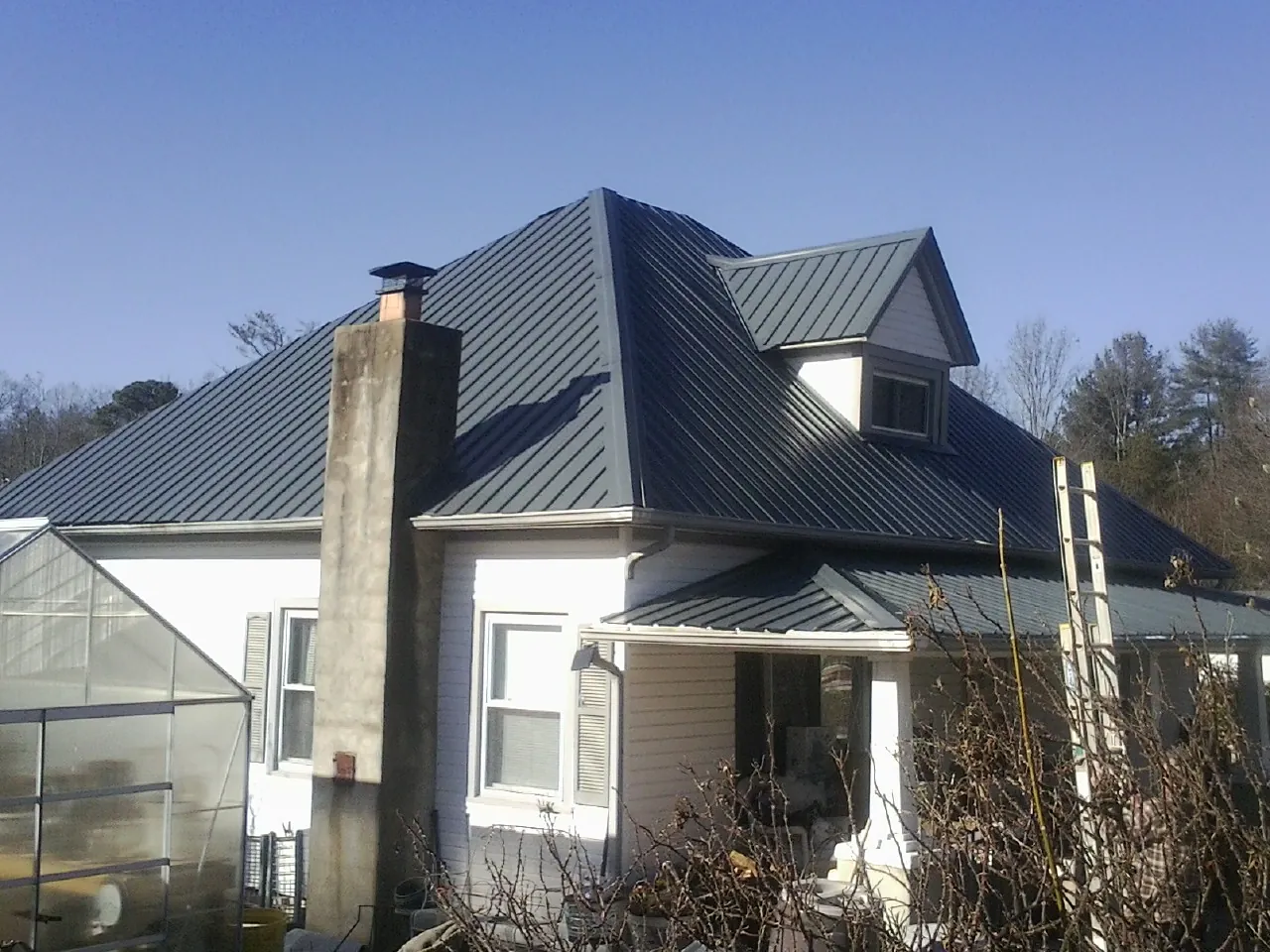 Dark blue standing seam metal roof on a white farmhouse with dormer — Slate & Tile Roof Repair by Roofing Brothers in Lyme