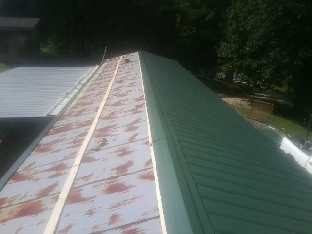 Old rusted panels beside newly installed green metal roofing — Wind Damage Roof Repair by Roofing Brothers in Lyme