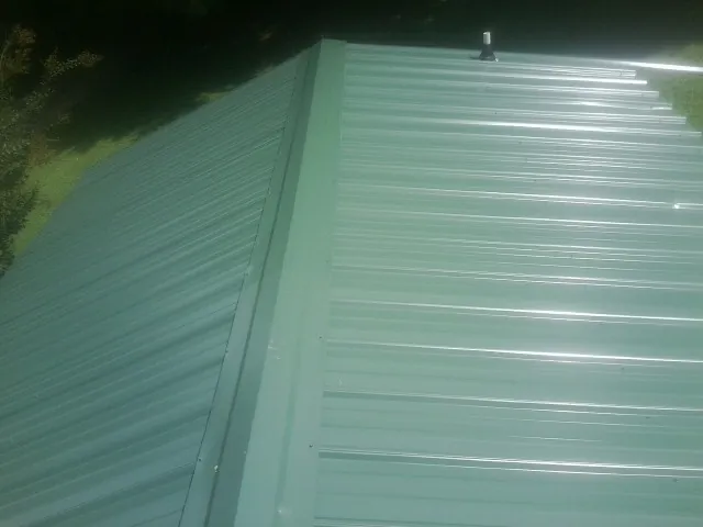 New green metal panels meeting at the ridge of a roof — Flat Roof Repair work by our crew in Lyme
