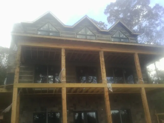 Dormers and porch framing on a large log home under construction — Roof Coating work by our crew in Lyme