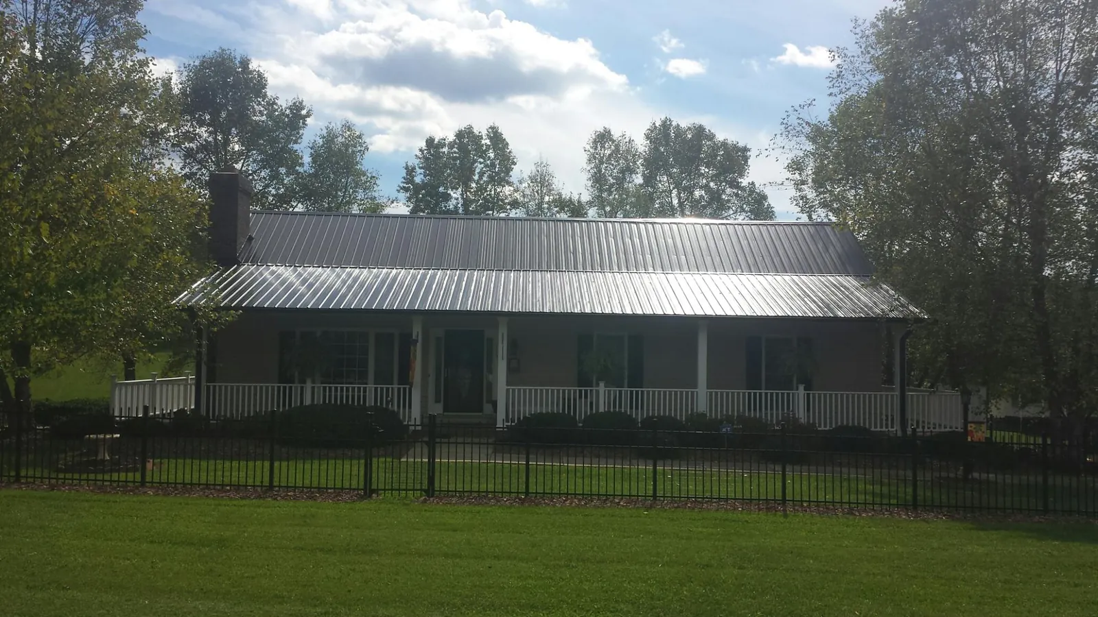 Gray metal roof on a brick ranch with a full width front porch — Gutter Guard Installation work by our crew in Lyme
