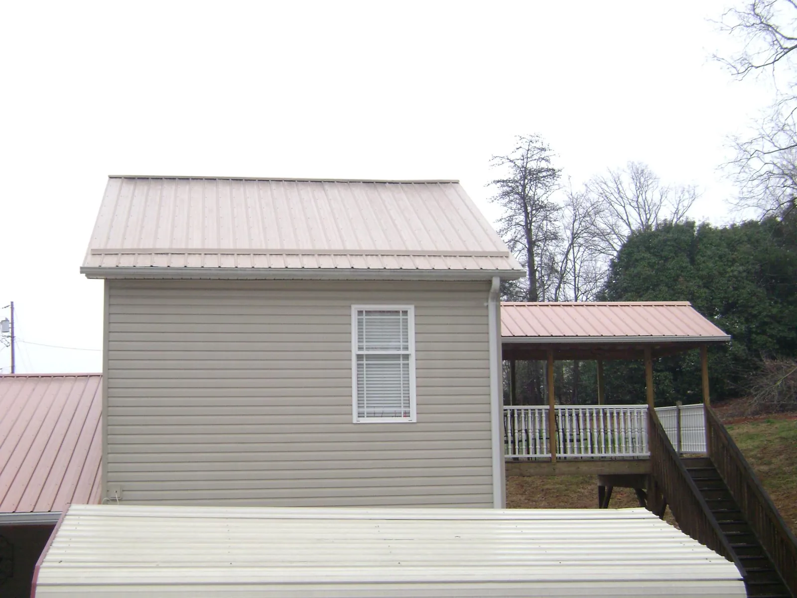 Tan metal roofs on a two story addition and attached porch, from a Roof Replacement job in Lyme