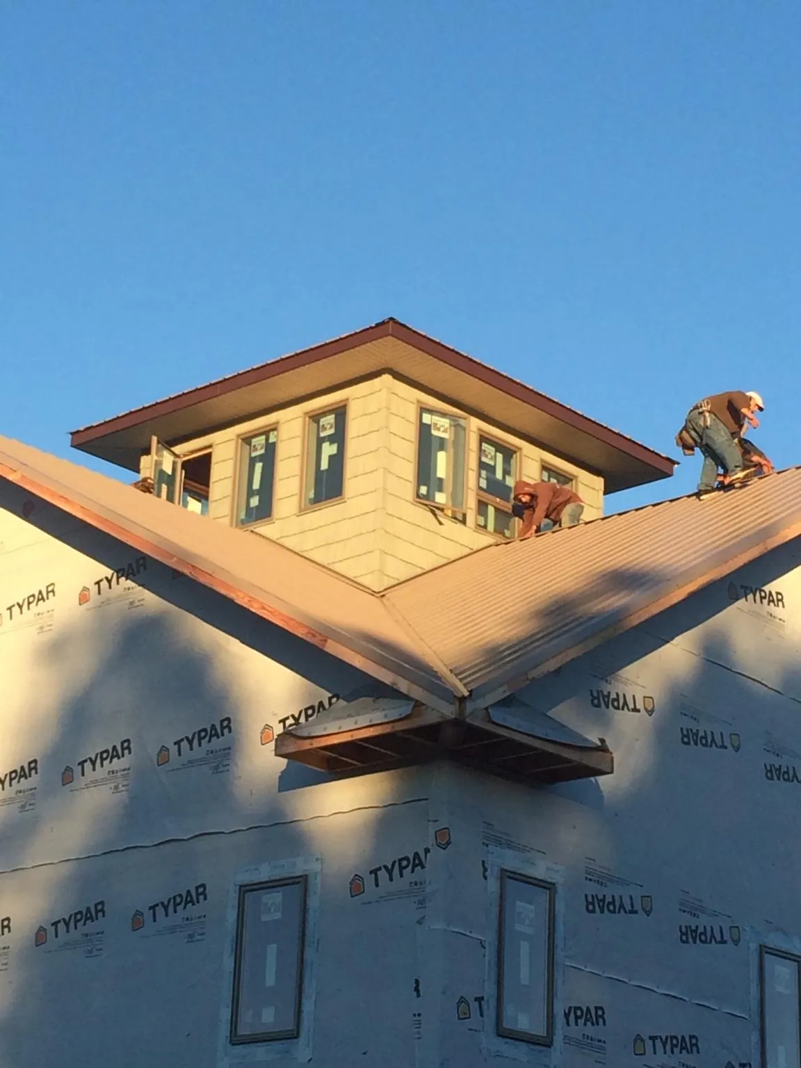 Roofers working around a rooftop cupola on a new metal roof at sunset — Roof Waterproofing in Lyme by Roofing Brothers